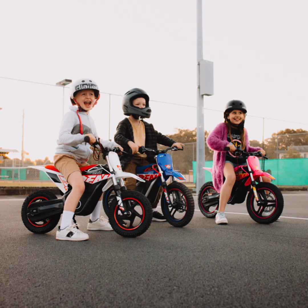 Na sliki so prikazana tri električna kolesa, namenjena otrokom. Znamka teh koles je "Apollo", model pa je "Olala SX E500". Otroci se veselijo vožnje, oblečeni so v čelade in udobna oblačila, kar kaže na varno in zabavno izkušnjo. Kolesa so v različnih barvah, kar dodatno pritegne pozornost.