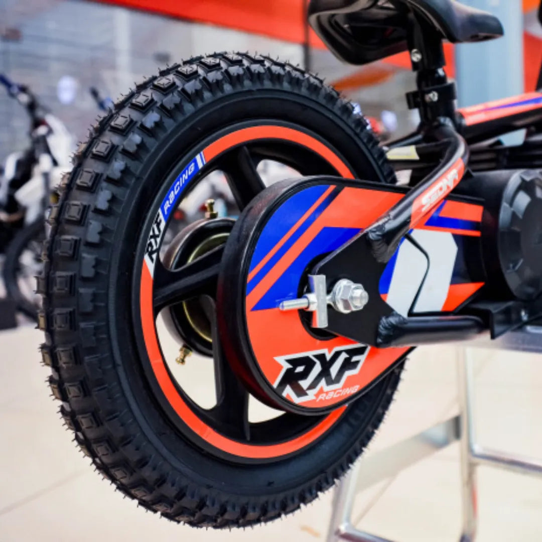 Izdelek je električno kolo, znamke Apollo, model Sedna 12 RXF. Na sliki je prikazan zadnji kolesni del kolesa, ki ima športno zasnovo z izrazitim profilom pnevmatike in barvnim dizajnom v rdeči, modri in črni barvi. Vidna je tudi oznaka RXF Racing, kar nakazuje na športno usmerjenost kolesa.