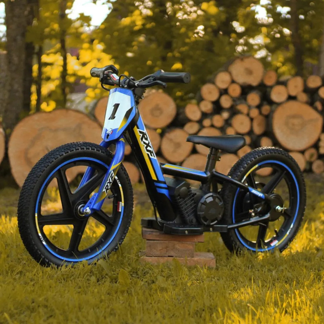 Izdelek je električno kolo, znamke RXF, model Apollo Sedna 16 RXF. Na sliki je vidno kolo z modro in rumeno barvno kombinacijo, ki ima široke gume in športen dizajn. Kolo je postavljeno na travnato površino, v ozadju pa so vidne sečnje dreves, kar ustvarja naravno okolje.