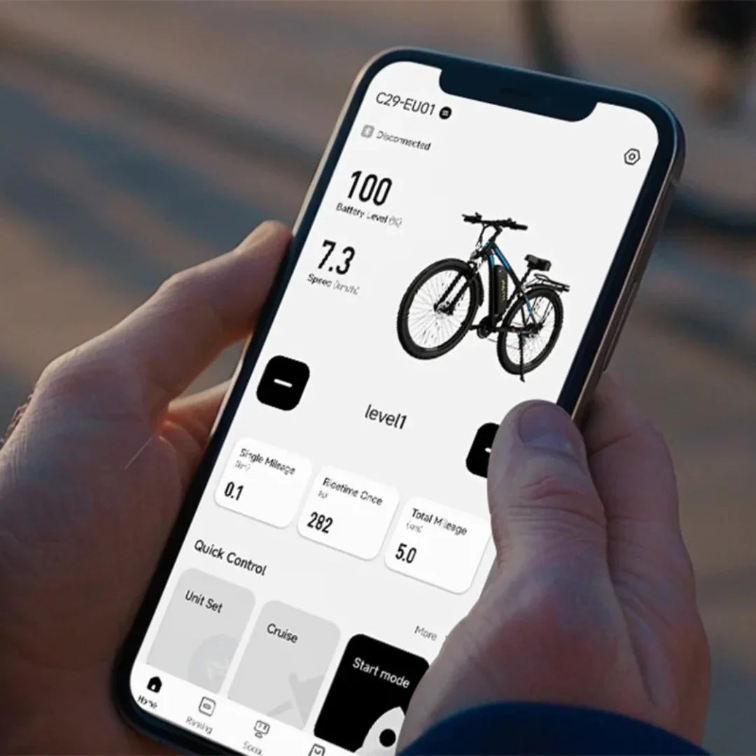 Na sliki je prikaz električnega kolesa znamke Duotts, model C29. Na zaslonu pametnega telefona so vidni podatki o bateriji, hitrosti in drugih funkcijah kolesa. Uporabnik drži telefon in spremlja informacije, kot so prevožena razdalja in nivo moči. Kolo ima sodoben dizajn in je opremljeno z debelimi pnevmatikami, kar nakazuje na njegovo primernost za različne terene.