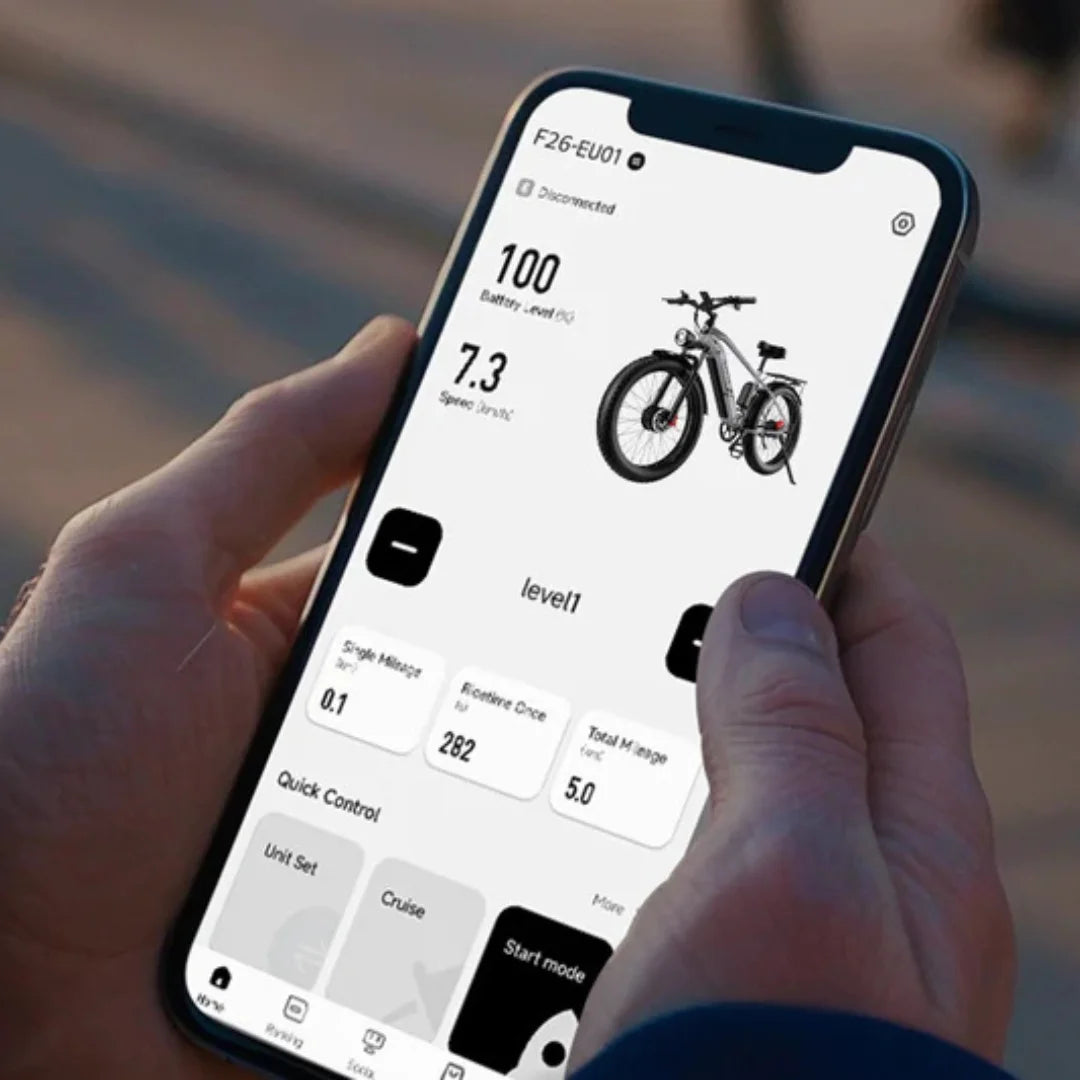 Na sliki je prikaz aplikacije za upravljanje električnim kolesom, model F26, znamke Duotts. Uporabnik drži telefon, na katerem so prikazani podatki o bateriji, hitrosti in drugih nastavitvah kolesa. Na zaslonu je vidna tudi ilustracija kolesa, kar omogoča enostavno spremljanje njegovega delovanja.