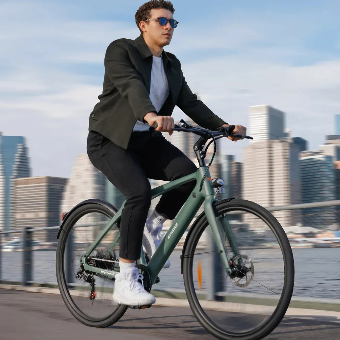 Na sliki je električno kolo znamke Engwe, model Mapfour N1 Air. Prikazuje moškega, ki vozi kolo po mestni promenadi, obdanem z modernimi zgradbami. Kolo ima minimalističen dizajn v zeleni barvi, moški pa nosi sončna očala in športna oblačila.