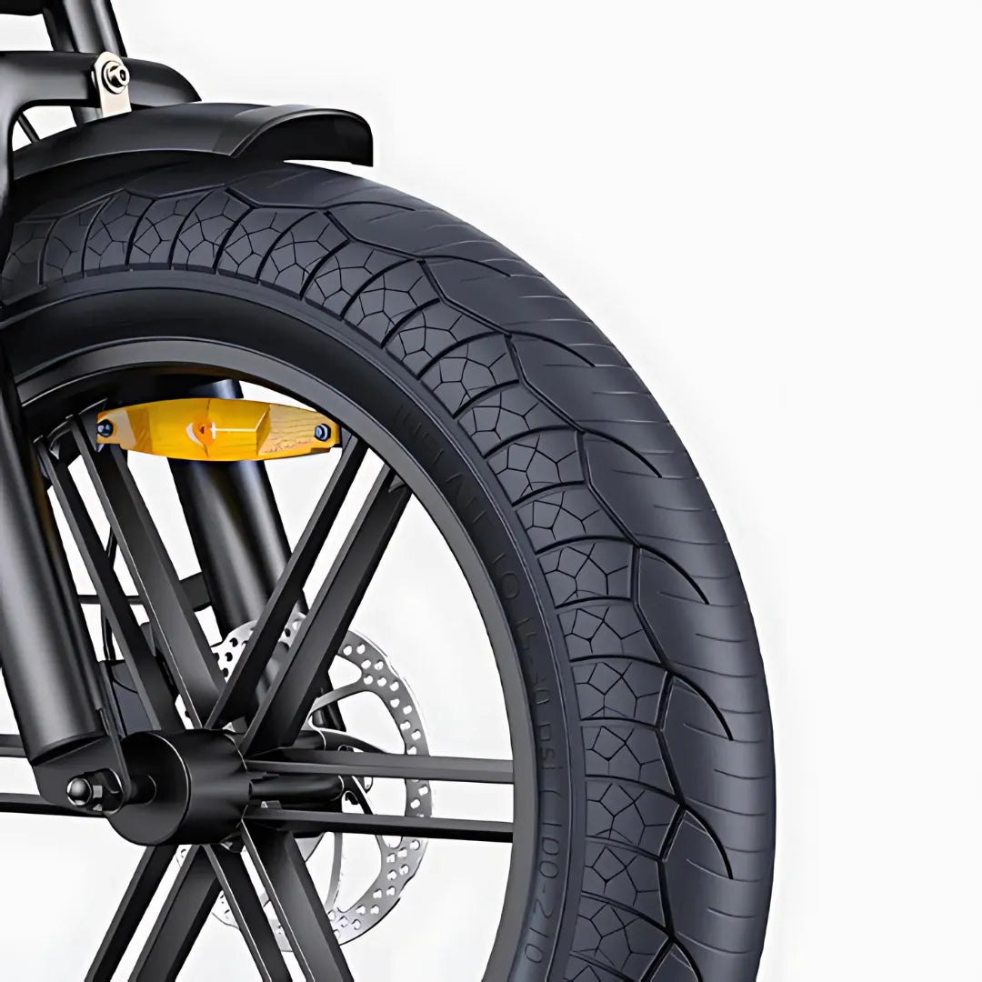 Izdelek na sliki je električno kolo, model Engwe M1. Na sliki je prikazan del sprednjega kolesa, ki vključuje široko pnevmatiko z izrazitim profilom, kar nakazuje na dobro oprijemljivost. Vidna je tudi zavora in del okvirja, kar kaže na robustno zasnovo kolesa.