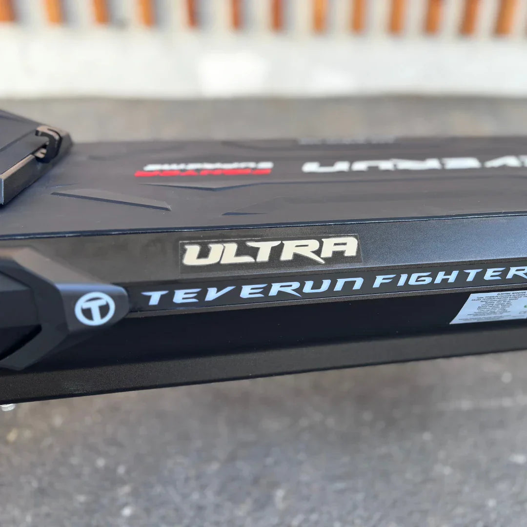 Izdelek je električni skiro, znamke Teverun, model Fighter Supreme 7260 Ultra. Na sliki je vidna stranska površina skiroja, kjer so jasno označeni imeni modela in znamke. Površina je temno obarvana, z modernim dizajnom in teksturo, ki daje občutek trpežnosti.