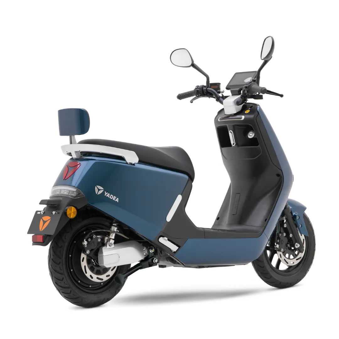 Električni skuter Yadea G5 v modri barvi z elegantnim dizajnom, parkiran in nagnjen, da prikaže podrobnosti.