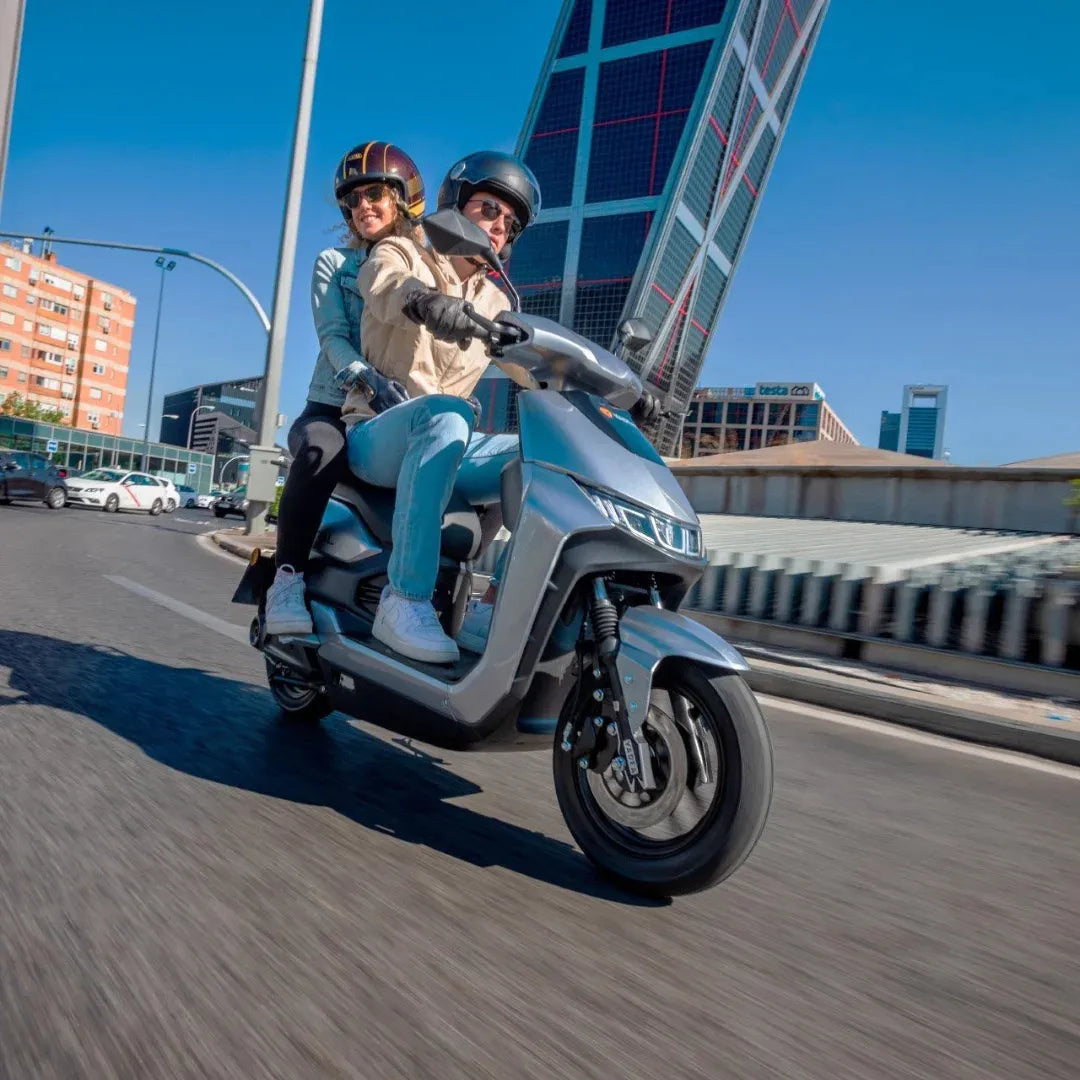 Par se vozi z električnim skuterjem Yadea T9l na sončni urbani ulici.