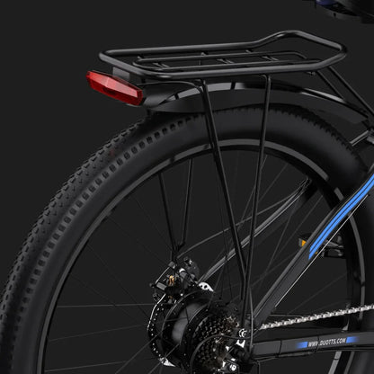 Izdelek na sliki je električno kolo znamke Duotts, model C29. Na sliki je vidna zadnja stran kolesa z nosilcem za prtljago in rdečo lučjo, kar nakazuje na funkcionalnost za prevoz in varnost. Kolo ima široke gume, kar je značilno za terenska kolesa.