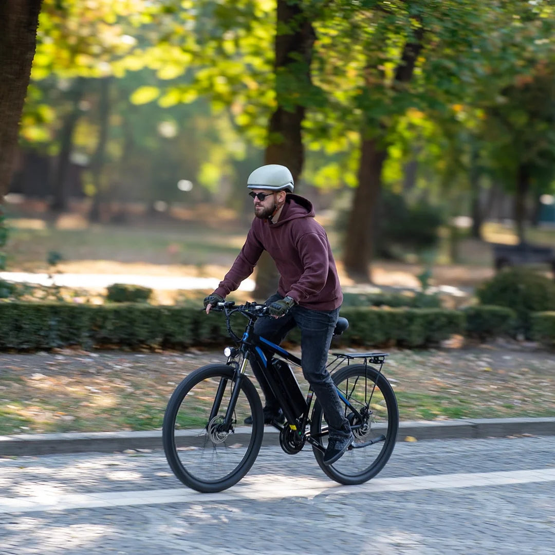 Oseba se vozi z električnim kolesom Duotts C29 skozi park na sončen dan.
