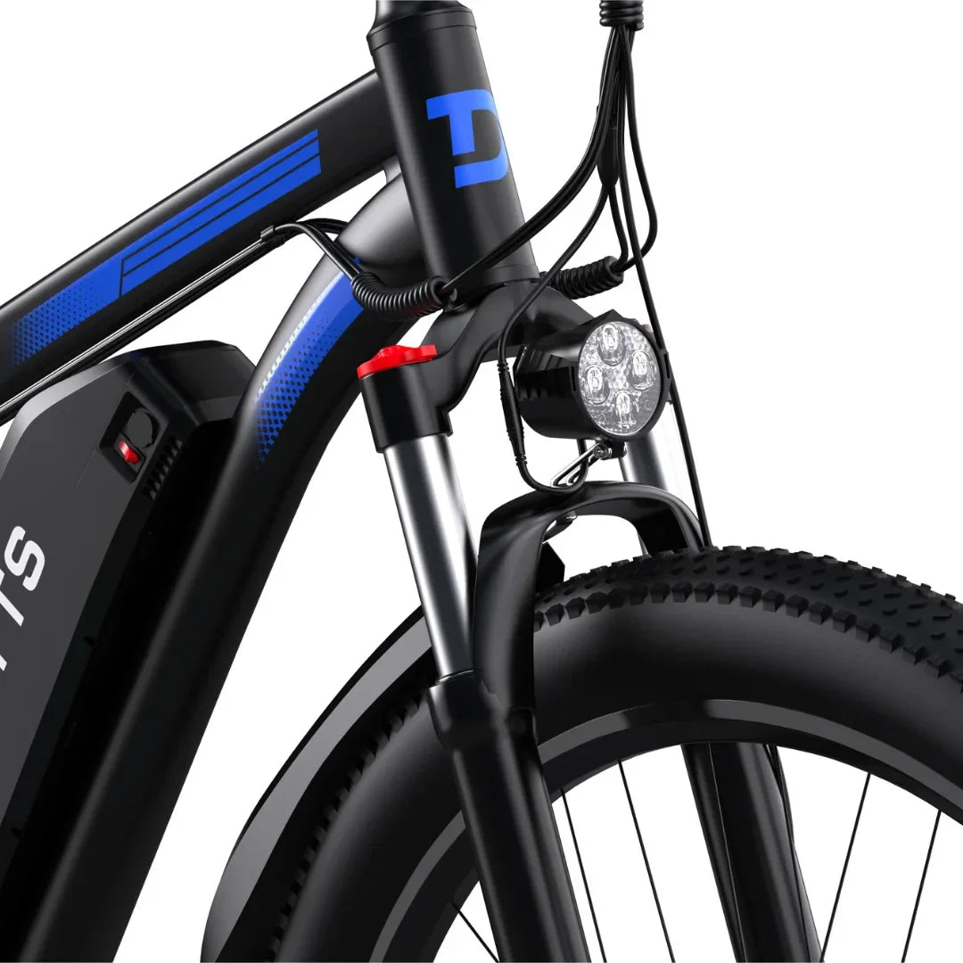 Izdelek je električno kolo, model Duotts C29. Na sliki je vidna sprednja vilica kolesa, ki vključuje LED luč za osvetlitev, ter del okvirja s črno in modro barvo. Kolo ima široke gume, kar nakazuje na primernost za različne terene. Viden je tudi akumulator, kar potrjuje, da gre za električno različico kolesa.