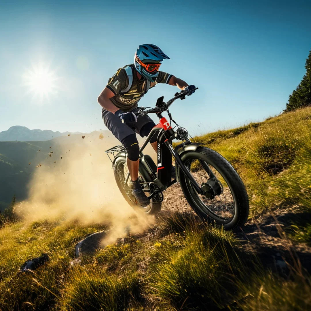 Na sliki je električno kolo model "F26" znamke Duotts. Kolo je v akciji, saj ga vozi kolesar po travnati poti, obkrožen z naravo. Kolesar nosi zaščitno čelado in očala, kar kaže na športno aktivnost. V ozadju so vidne gore in sonce, kar ustvarja dinamično in privlačno vzdušje. Kolo ima široke pnevmatike in robustno zasnovo, kar je primerno za vožnjo po zahtevnejših terenih.