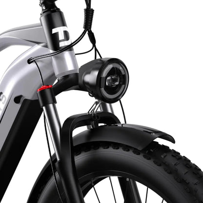 Izdelek je električno kolo, model Duotts F26. Na sliki je prikazan sprednji del kolesa, kjer so vidni okvir, sprednja luč in široka guma z grobim profilom, kar nakazuje na primernost za različne terene. Kolo ima tudi vzmetenje in zaščitni blatnik.