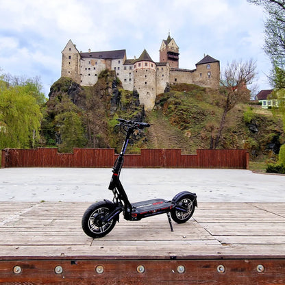 Električni skiro Dualtron City parkiran na leseni ploščadi z gradom v ozadju.