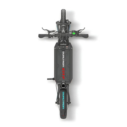 Na sliki je električni skiro, model Dualtron City. Vidna je zgornja stran skiroja, kjer so prikazani krmili, ročaji in električni sistem. Na sredini se nahaja baterija, označena z imenom modela, in vidni so tudi gumi ter zadnje kolo. Skuter ima robustno zasnovo, kar nakazuje na njegovo zmogljivost in trajnost.