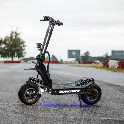 Električni skiro Dualtron X Limited parkiran na dirkališču z oblačnim nebom v ozadju.