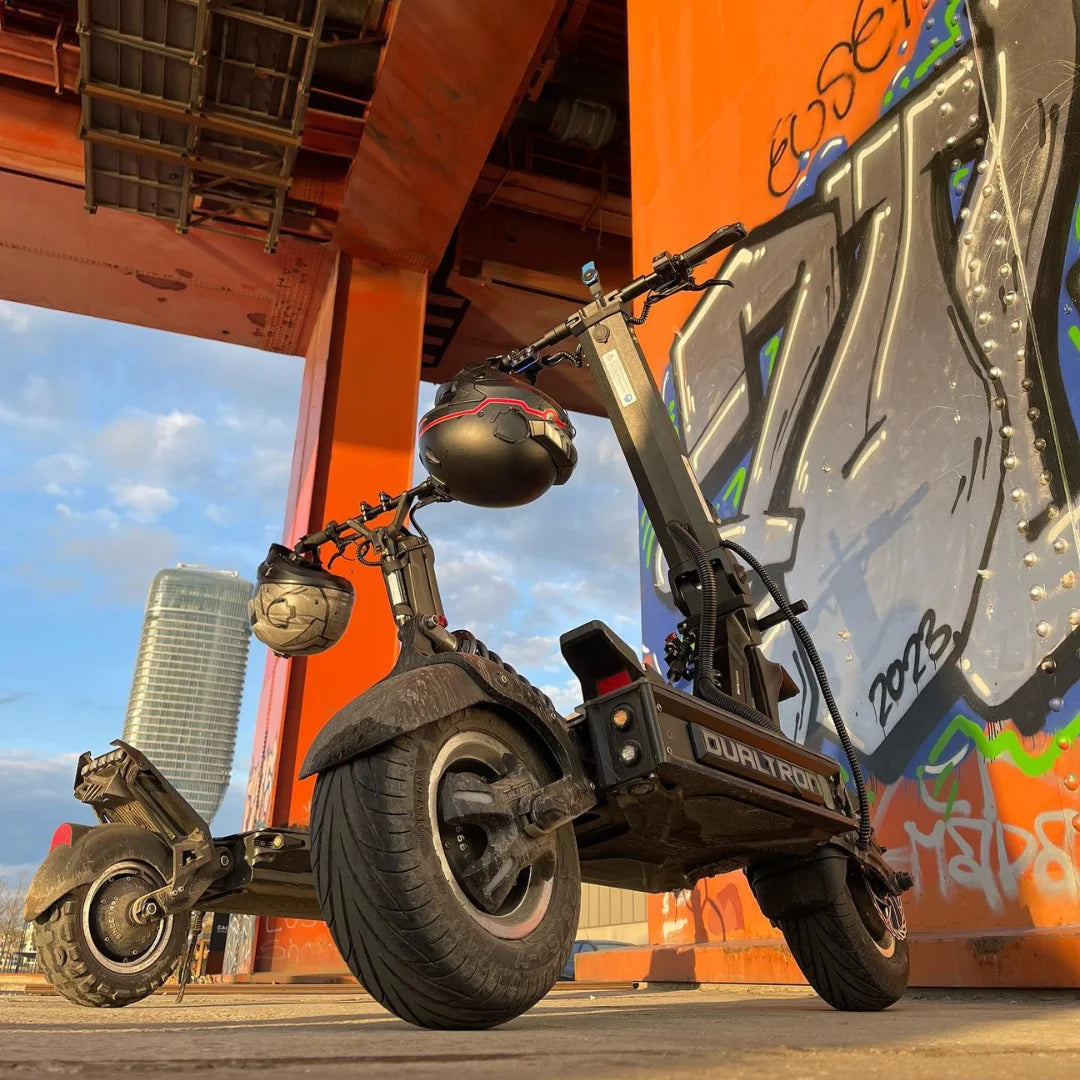 Električni skiro Dualtron X Limited parkiran pod urbano strukturo z grafiti.