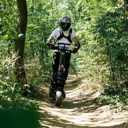 Oseba se vozi z električnim skirojem Dualtron X Limited po gozdni poti.
