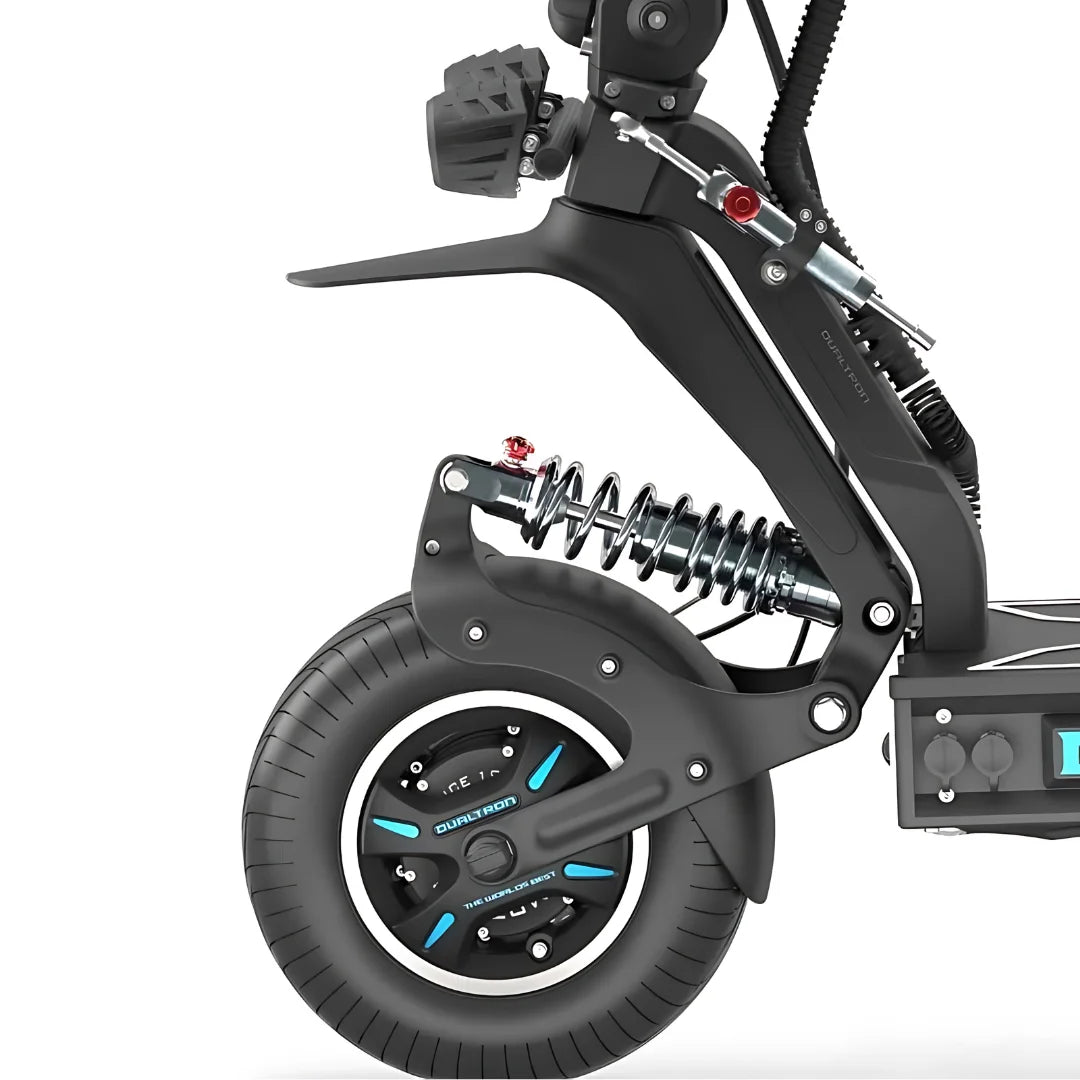 Na sliki je električni skiro znamke Dualtron, model X Limited. Vidna je zadnja stran skiroja, kjer se nahajajo robustna kolesa z debelim profilom, kar omogoča boljšo stabilnost in udobje pri vožnji. Prav tako so vidni elementi vzmetenja, ki prispevajo k blaženju udarcev na neravnih površinah. Oblika je moderna in športna, kar nakazuje na zmogljivost in hitrost tega modela.