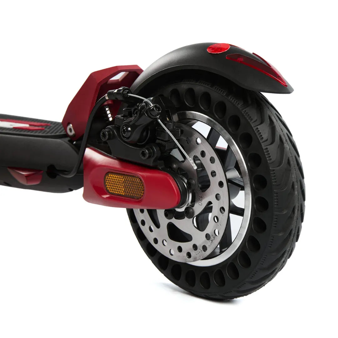 Izdelek je električni skiro, model Eco Speed Mini. Na sliki je vidna zadnja kolesa skiroja, ki ima široko pnevmatiko z luknjami za boljšo absorpcijo udarcev. Opremljen je z disk zavornim sistemom, kar zagotavlja učinkovito zaviranje. Rdeča barva nekaterih delov daje skiroju športen videz. Vidna je tudi odsevna lučka za večjo varnost med vožnjo.
