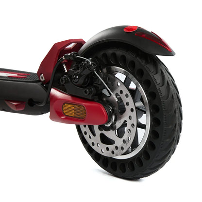 Izdelek je električni skiro, model Eco Speed Mini. Na sliki je vidna zadnja kolesa skiroja, ki ima široko pnevmatiko z luknjami za boljšo absorpcijo udarcev. Opremljen je z disk zavornim sistemom, kar zagotavlja učinkovito zaviranje. Rdeča barva nekaterih delov daje skiroju športen videz. Vidna je tudi odsevna lučka za večjo varnost med vožnjo.
