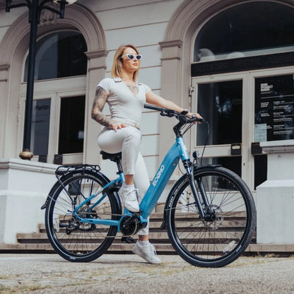 Oseba s sončnimi očali pozira na električnem kolesu Econo Mare City Eec4lk pred stavbo.