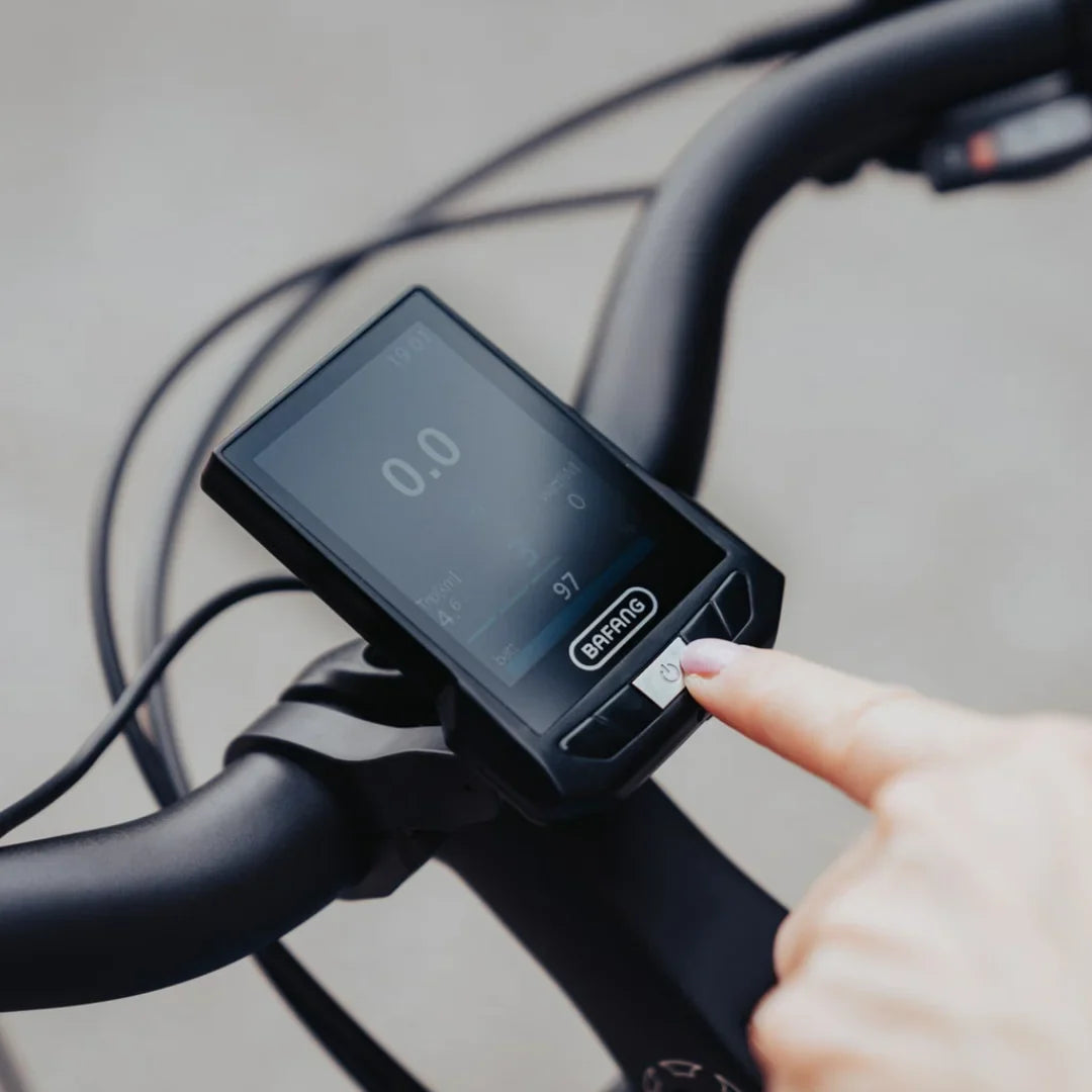 Izdelek je električno kolo, model Econo Mare City EEC4LK. Na sliki je prikazan zaslon, ki je nameščen na krmilu kolesa, kjer uporabnik pritiska na gumb. Zaslon prikazuje različne podatke, kot so hitrost in nivo baterije, kar omogoča enostavno spremljanje delovanja kolesa med vožnjo.