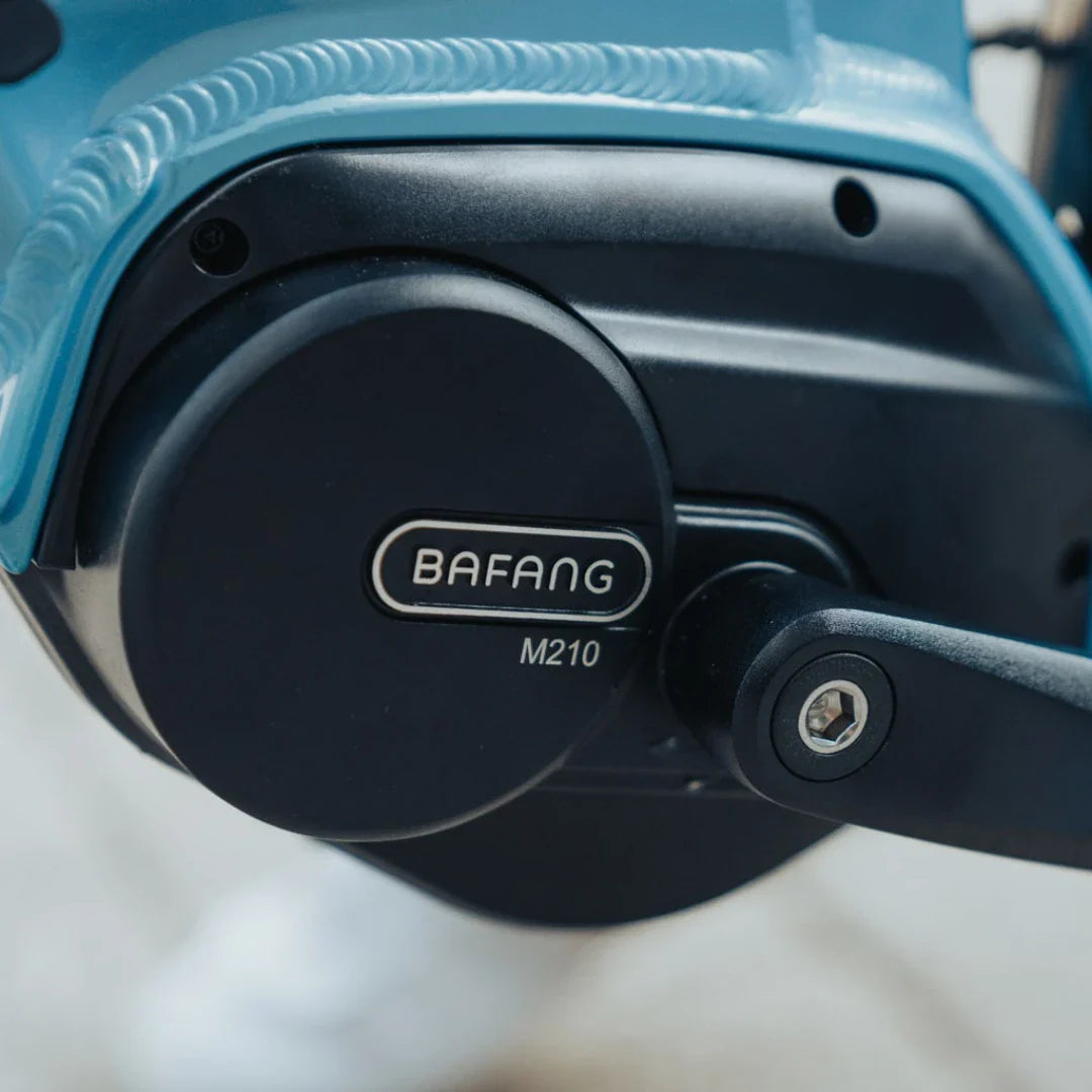 Izdelek na sliki je električno kolo. Znamka je Bafang, model pa M210. Na sliki je vidna električna motorna enota, ki je nameščena na okvirju kolesa, kar nakazuje na sistem za pomoč pri pedalanju. Barva okvirja je modra, kar daje kolesu sodoben videz.