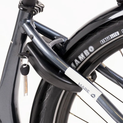 Izdelek je električno kolo, znamke Mare, model Econo Mare City. Na sliki je vidna struktura kolesa, ki vključuje okvir v temno modri barvi ter ključavnico, pritrjeno na okvir. Prav tako je opazna pnevmatika z oznako "Mambo", kar nakazuje na kakovostne gume. Kolo ima sodoben dizajn, kar ga naredi primernega za mestno vožnjo.