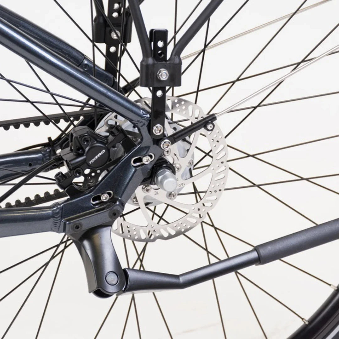 Izdelek je električno kolo, model Econo Mare City. Na sliki je prikazan zadnji del kolesa, kjer so vidni zavore in del okvirja. Oprema vključuje disk zavore, kar zagotavlja učinkovito ustavljanje, ter del mehanizma, ki omogoča gladko delovanje. Barva okvirja je temna, kar daje kolesu sodoben videz.