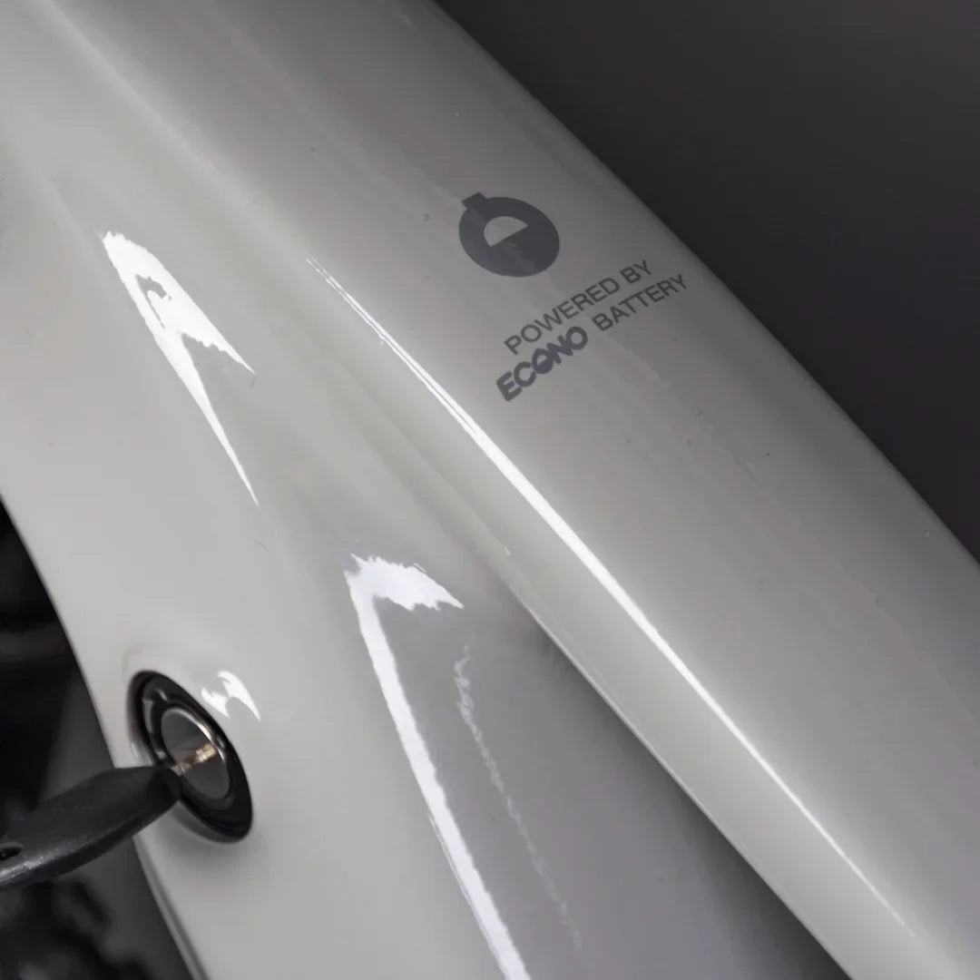 Izdelek je električno kolo, znamke Econo, model Pantera C6 120. Na sliki je vidna bela površina okvirja kolesa z oznako "Powered by Econo Battery" ter ključavnica za baterijo. Kolo ima sodoben in eleganten dizajn, kar nakazuje na uporabnost in funkcionalnost.