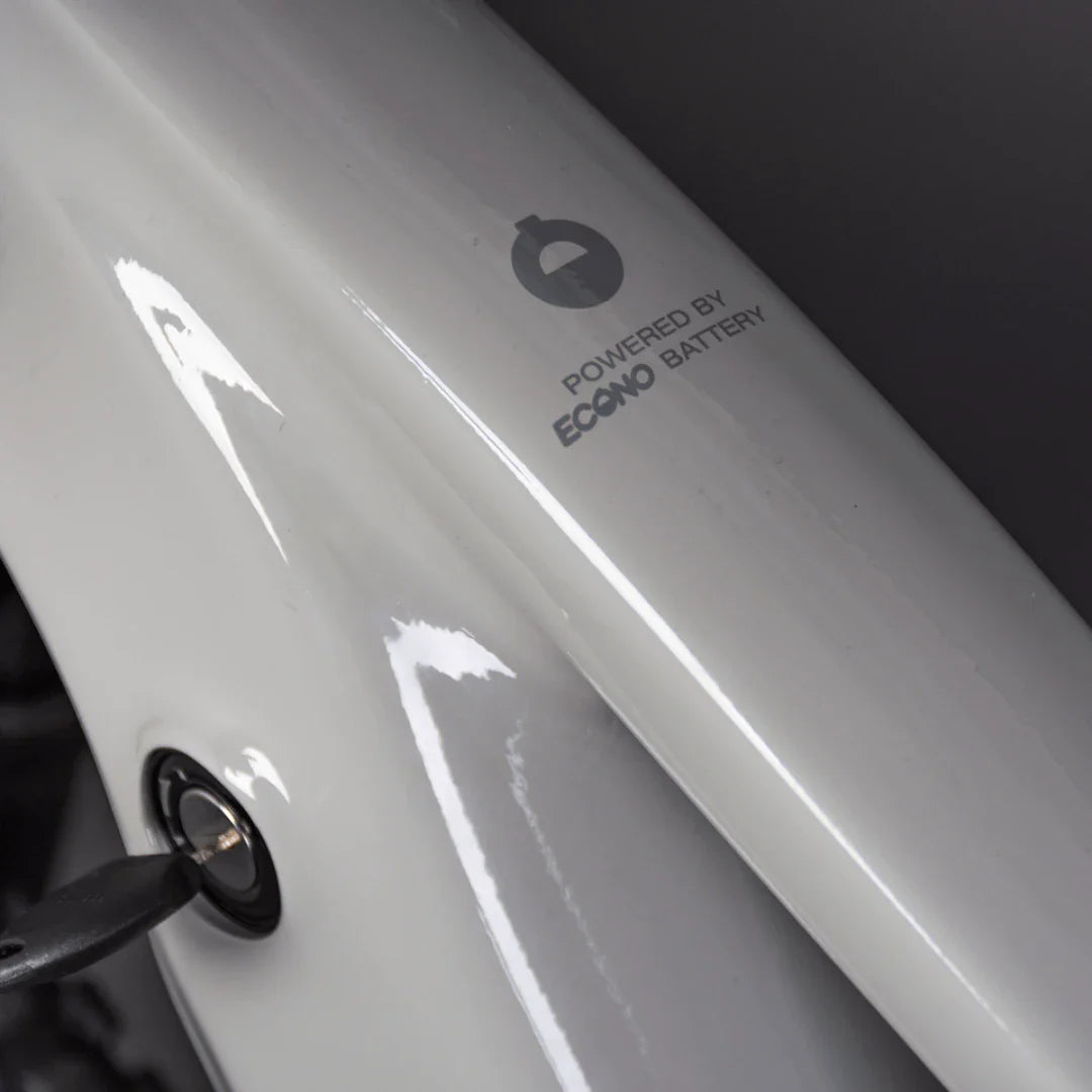 Izdelek je električno kolo, model Econo Pantera C9 160. Na sliki je del okvirja kolesa, ki prikazuje oznako "Powered by Econo Battery", kar nakazuje na uporabo Econo baterije za napajanje. Vidna je tudi ključavnica, kar pomeni, da je kolo opremljeno z varnostnim sistemom. Barva okvirja je svetla in sijoča.