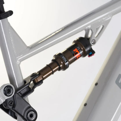 Izdelek je električno kolo, znamke Econo, model Pantera C9 160. Na sliki je prikazan del okvirja kolesa, kjer je vidna vzmetna enota, ki je del sistema vzmetenja. Vzmetna enota je označena z logotipom FOX in je zasnovana za izboljšanje udobja in nadzora pri vožnji po neravnem terenu.