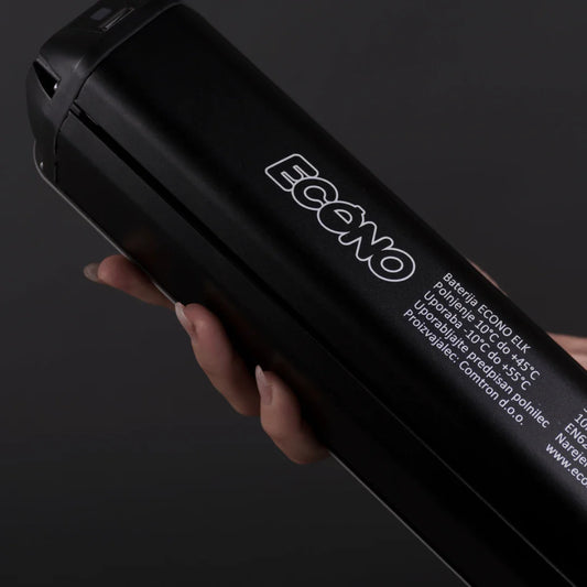 Izdelek na sliki je električno kolo, natančneje baterija za model Econo Pantera SUV C6. Znamka je Econo, baterija pa je v črni barvi. Na sliki je prikazana roka, ki drži baterijo, na kateri so navedene informacije o polnjenju in temperaturi delovanja.