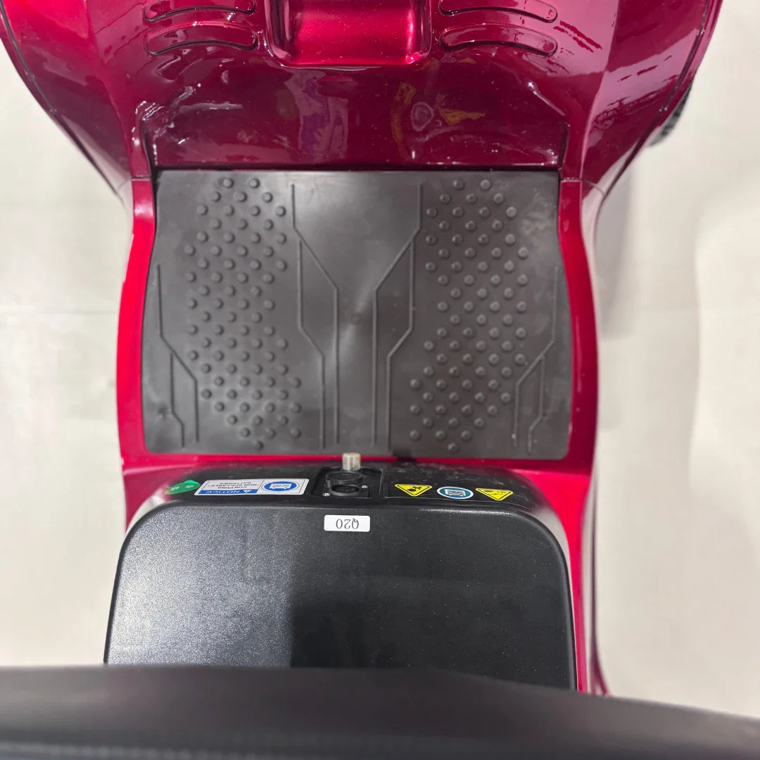 Izdelek je električni mobilni voziček, model Eco Speed Senior. Na sliki je vidna platforma vozička, ki ima gumirano površino za boljši oprijem, ter kontrolna enota z različnimi gumbi in oznakami. Barva vozička je rdeča, kar daje dinamičen videz.
