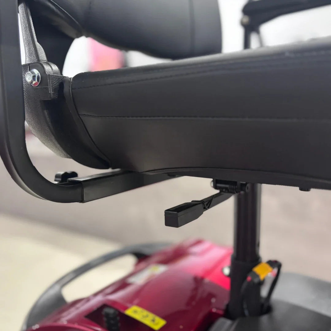 Izdelek je električni mobilni voziček, specifično model Eco Speed Senior. Na sliki je prikazan del sedeža vozička, ki je oblazinjen in ima črno barvo. Vidna je tudi podpora za naslon, ki je pritrjena na okvir vozička. Spodaj se nahaja mehanizem, ki omogoča prilagoditev višine sedeža. Celoten dizajn je zasnovan za udobno in enostavno uporabo, kar je pomembno za starejše uporabnike.