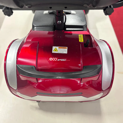 Izdelek je električni mobilni voziček, model ECO SPEED. Na sliki je vidna zgornja površina vozička, ki je v rdeči barvi s srebrnimi detajli. Na sprednjem delu je logo "ECO SPEED" ter opozorilne nalepke. Voziček je zasnovan za udobno in enostavno premikanje, kar je še posebej koristno za starejše uporabnike.