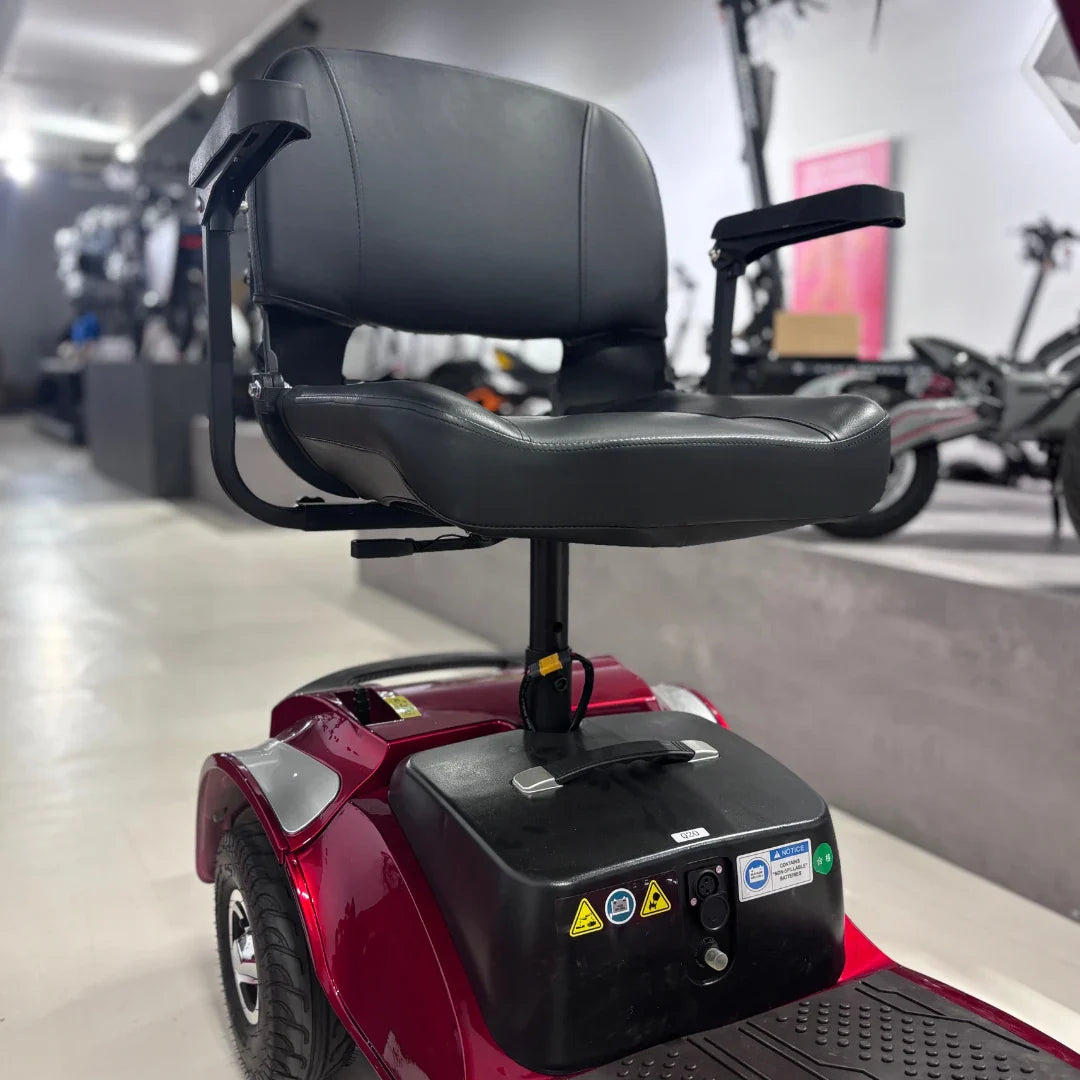 Izdelek je električni mobilni voziček, model Eco Speed Senior. Na sliki je vidna udobna črna sedežna enota z naslonjalom in ročaji, ki omogočajo enostavno upravljanje. Voziček je v rdeči barvi in ima robustno zasnovo, kar nakazuje na njegovo stabilnost in primernost za uporabo na različnih površinah. V ozadju so vidni tudi drugi električni prevozi, kar nakazuje, da je izdelek del širše ponudbe mobilnih rešitev.