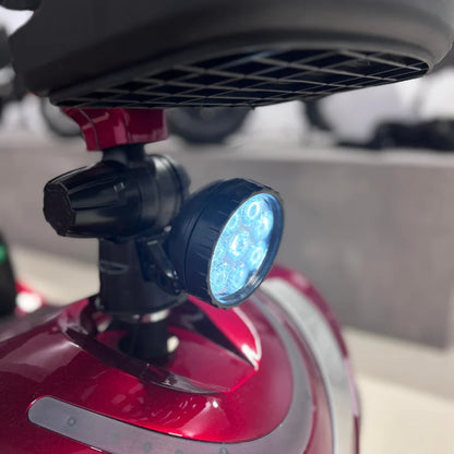 Izdelek je električni mobilni voziček, model Eco Speed Senior. Na sliki je prikazana svetilka, ki je nameščena na vozičku, in je zasnovana za izboljšanje vidnosti. Voziček ima rdečo barvo in aerodinamično obliko, kar nakazuje na udobno in praktično uporabo.