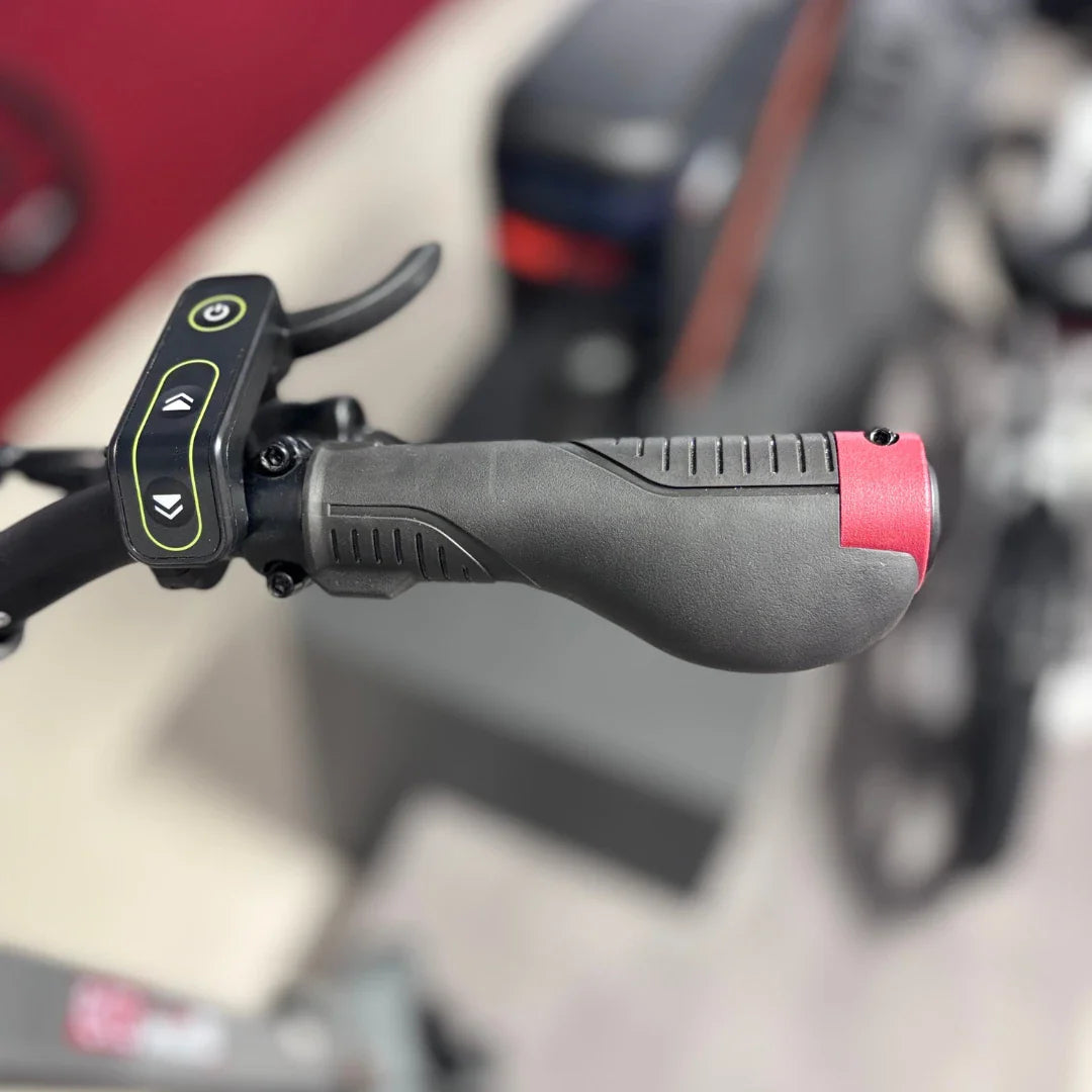 Izdelek je električni skiro, model Eco Speed 10X V2. Na sliki je prikazan del krmila, kjer so vidni ročaj in gumbi za upravljanje. Ročaj je oblikovan za udoben oprijem, gumbi pa omogočajo enostavno upravljanje hitrosti in delovanja skiroja. V ozadju so vidni tudi drugi deli skiroja.