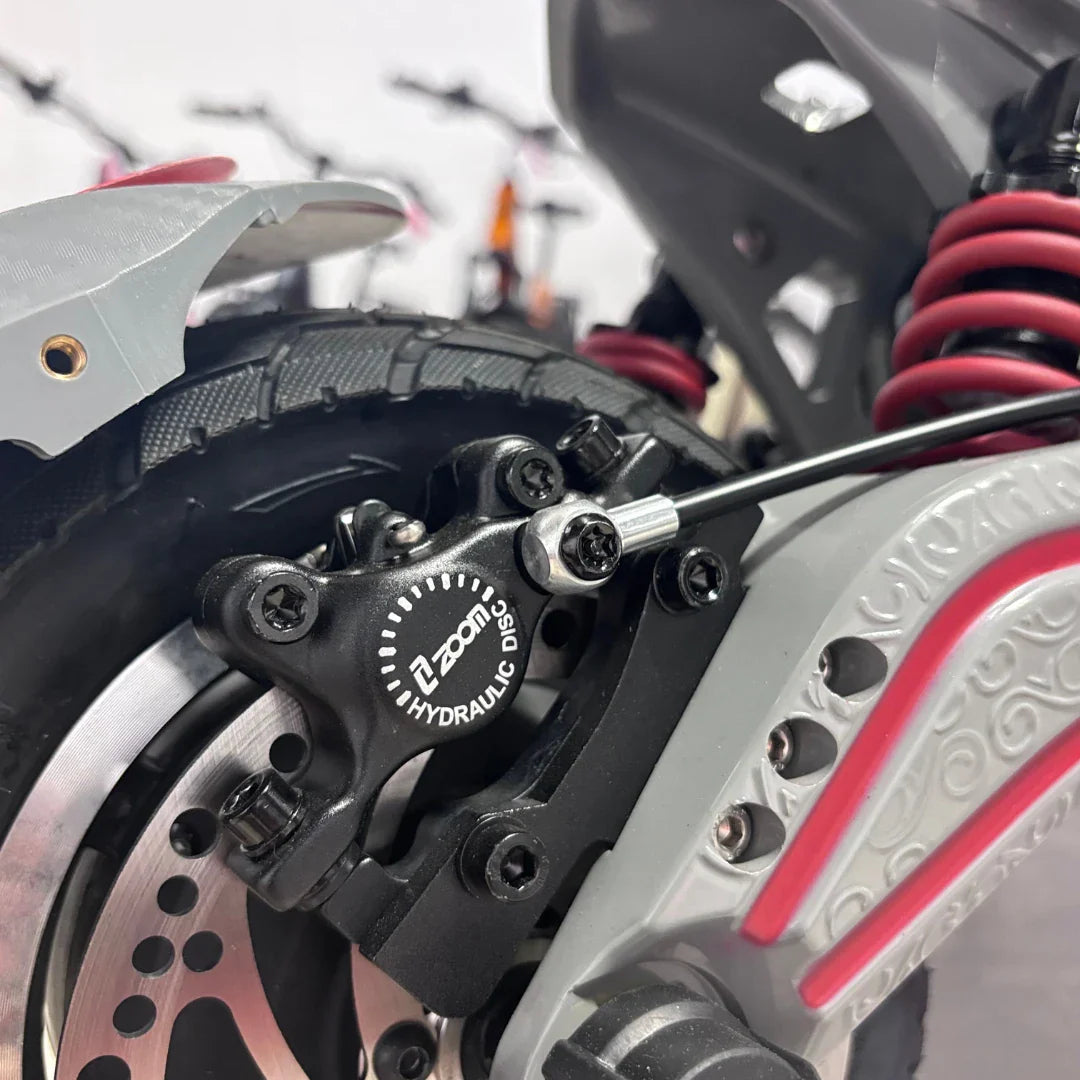 Izdelek na sliki je električni skiro, model Eco Speed 10X V2. Na sliki je prikazan del zavornega sistema, ki vključuje hidravlično zavoro znamke Zoom. Vidna je tudi pnevmatika in del okvirja skiroja, kar nakazuje na robustno konstrukcijo in zmogljivost.