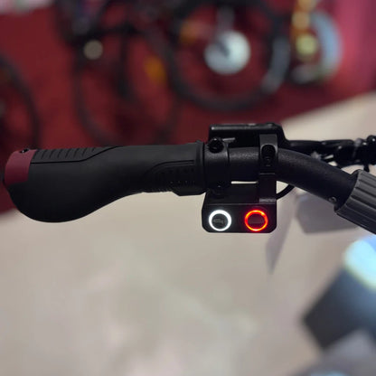 Na sliki je prikazan električni skiro, model Eco Speed 10X V2. Vidna je ročica za upravljanje, ki ima ergonomski dizajn, ter gumbi za vklop in izklop, ki sta označena z rdečo in belo barvo. Ozadje slike je zamegljeno, kar nakazuje, da je skiro postavljen v okolju, kjer so prisotni tudi drugi kolesarski izdelki.