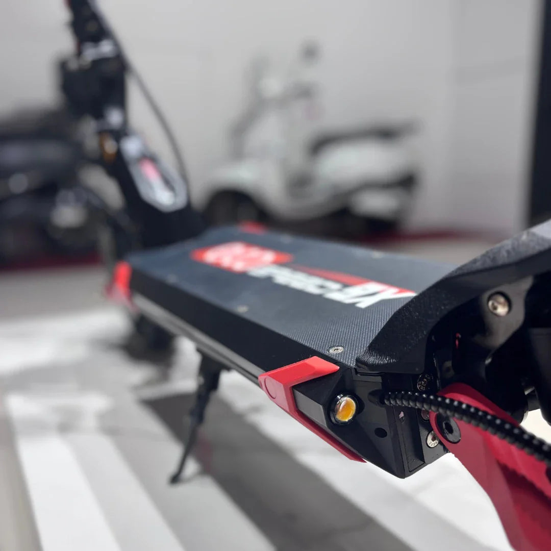 Izdelek na sliki je električni skiro, model Eco Speed 9X. Na sliki je vidna platforma skiroja s črno in rdečo barvno kombinacijo, ki vključuje tudi nekaj detajlov, kot so gumbi in osvetlitev. V ozadju so vidni še drugi električni skiroji, kar nakazuje, da gre za prodajno ali razstavno okolje.