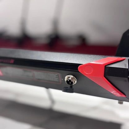 Na sliki je električni skiro, model Eco Speed 9X. Vidna je podrobnost iz spodnjega dela skiroja, kjer so prikazani rdeči plastični detajli ter priključki, ki verjetno služijo za polnjenje in povezovanje. Oznake in specifikacije na skiroju so del njegove zasnove, kar nakazuje na funkcionalnost in zmogljivosti izdelka.