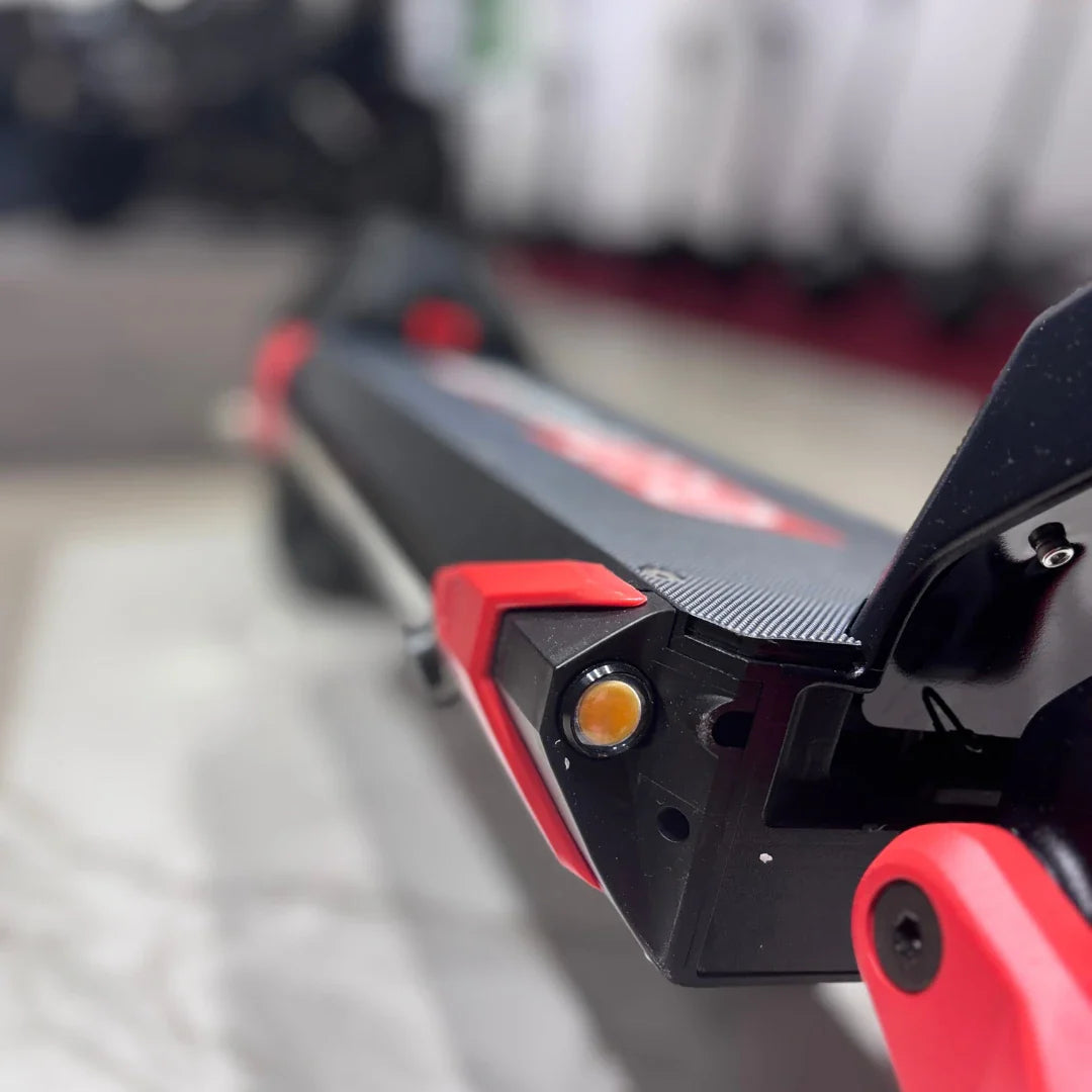 Na sliki je električni skiro model Eco Speed 9X. Vidna je del konstrukcije skiroja, ki vključuje rdeče in črne detajle ter lučko na sprednjem delu. Površina skiroja je teksturirana, kar omogoča boljši oprijem. V ozadju so delno vidni drugi skiroji.