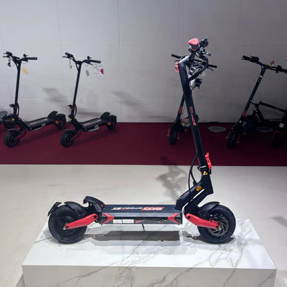 Izdelek na sliki je električni skiro, model Eco Speed 9X. Na sliki je prikazan skiro v črno-rdeči barvni kombinaciji, ki stoji na beli podlagi. V ozadju so vidni še drugi električni skiroji iste znamke. Skuter ima široke pnevmatike in robustno konstrukcijo, kar nakazuje na stabilnost in udobno vožnjo.