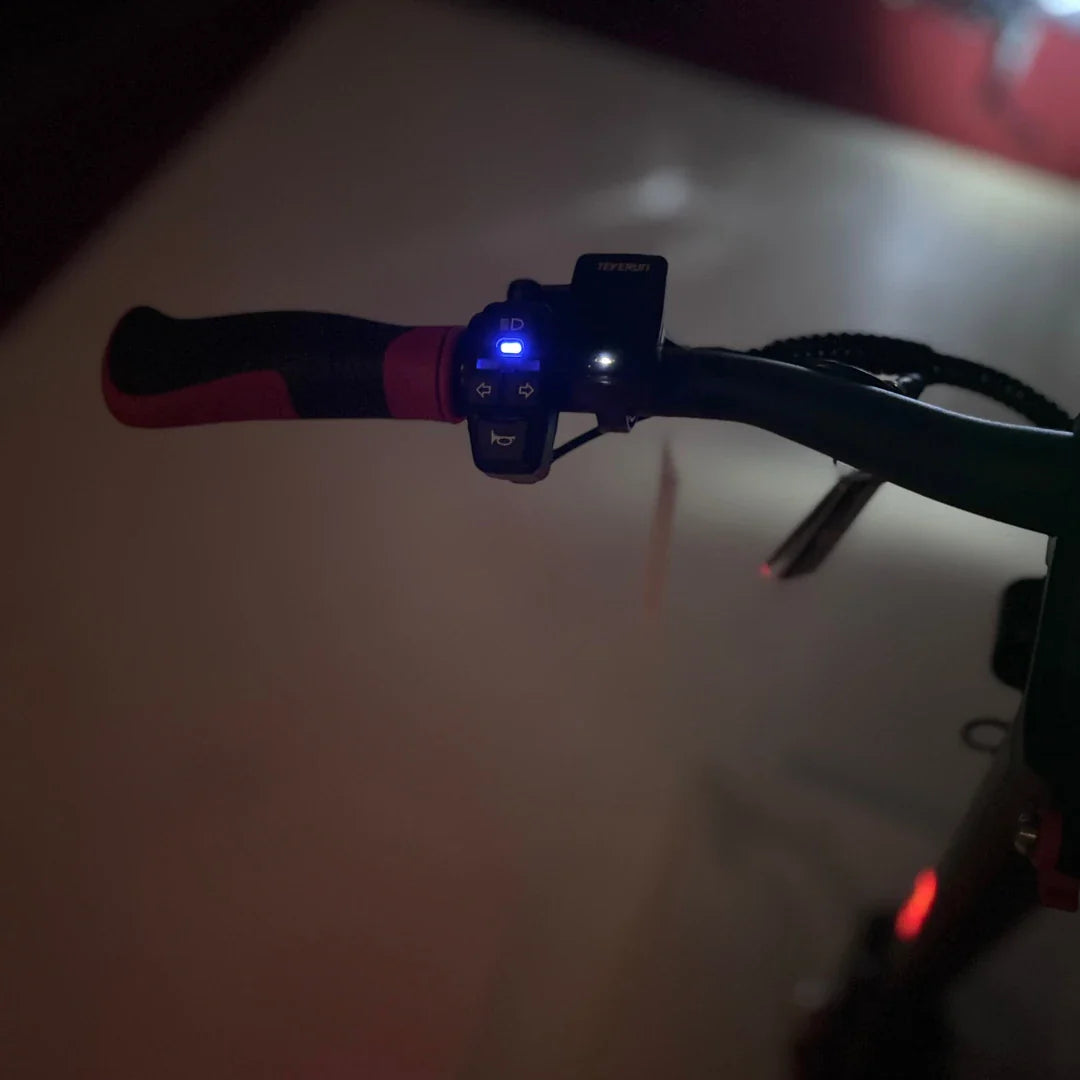 Na sliki je prikazan električni skiro, model Eco Speed 9X. Vidni so ročaji skiroja, na katerih so nameščeni gumbi za upravljanje in LED lučke. Gumbi omogočajo nadzor nad delovanjem skiroja, medtem ko LED lučke zagotavljajo vidnost v slabših svetlobnih pogojih. Skupna zasnova ročajev je ergonomična, kar prispeva k udobni vožnji.