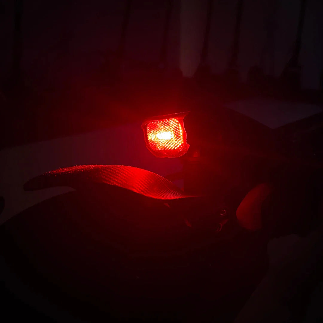 Na sliki je električni skiro model Eco Speed 9X. Vidna je zadnja lučka, ki sveti rdeče, kar nakazuje na varnostne funkcije skiroja. Lučka je zasnovana za boljšo vidnost v temi, kar je pomembno za varno vožnjo. Oprema skiroja vključuje tudi del, ki je lahko del krmila ali zadnjega dela, kar prispeva k njegovi funkcionalnosti.