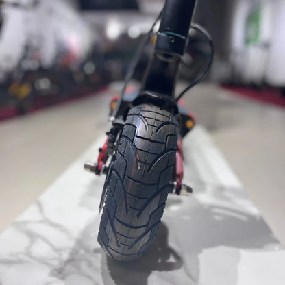 Izdelek je električni skiro, model Eco Speed 9X. Na sliki je prikazan zadnji del skiroja, kjer je vidna široka pnevmatika s profilom, ki je zasnovan za dobro oprijemljivost. V ozadju se vidi del prodajnega prostora z drugimi skiroji.