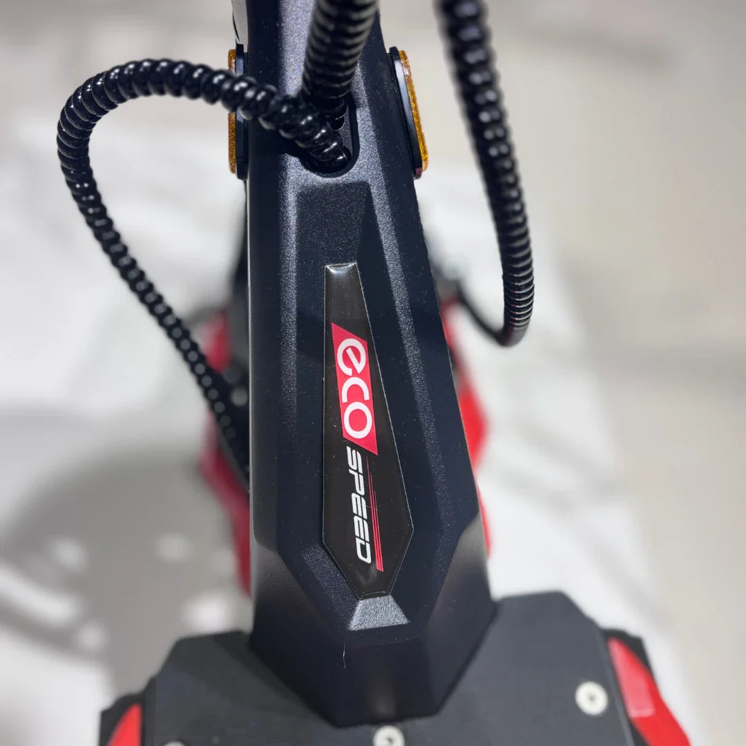 Izdelek na sliki je električni skiro, znamke Eco Speed, model 9X. Na sliki je vidna del skiroja, kjer je jasno prikazana oznaka znamke Eco Speed. Barvna kombinacija je temno siva s poudarki v rdeči barvi, kar daje izdelku sodoben in dinamičen videz. Opremljen je z različnimi kabli, kar nakazuje na električno delovanje.