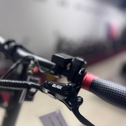 Izdelek je električni skiro, model "Eco Speed 9X". Na sliki so vidni del krmila skiroja, z ročajem, ki ima teksturirano površino za boljši oprijem, ter zavorni mehanizem z oznako "BLADE". V ozadju je del športne opreme, kar nakazuje, da je slika posneta v trgovini ali na razstavi.