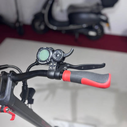 Izdelek je električni skiro, model Eco Speed 9. Na sliki je vidna ročica za upravljanje, zaslon za prikaz informacij ter gumijasti ročaji, ki zagotavljajo udoben oprijem. V ozadju je del drugega skiroja, kar nakazuje, da je izdelek del večje kolekcije.